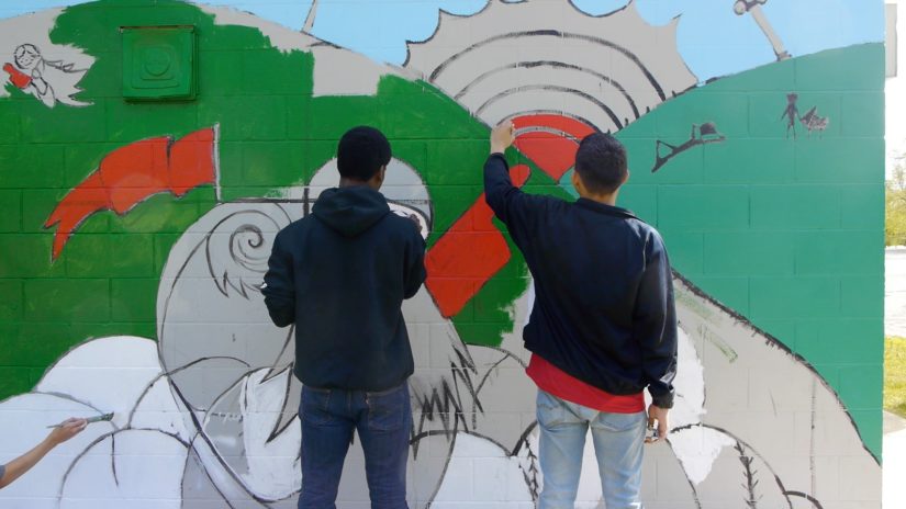 Two teens painting a mural.