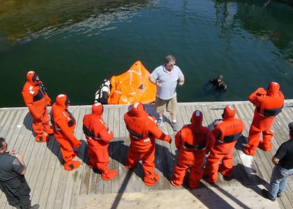 Fishermen in orange survival suits at a training class.